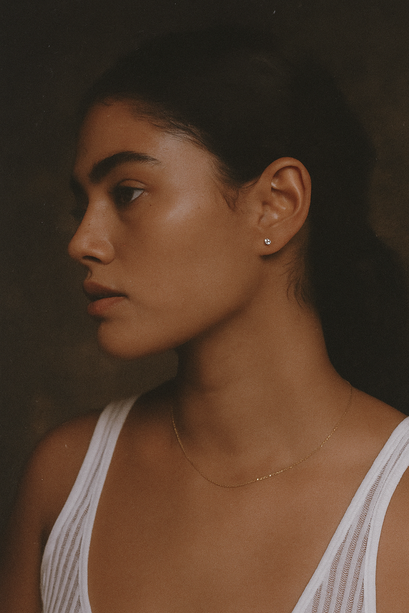 Woman wearing a delicate necklace against a dark background